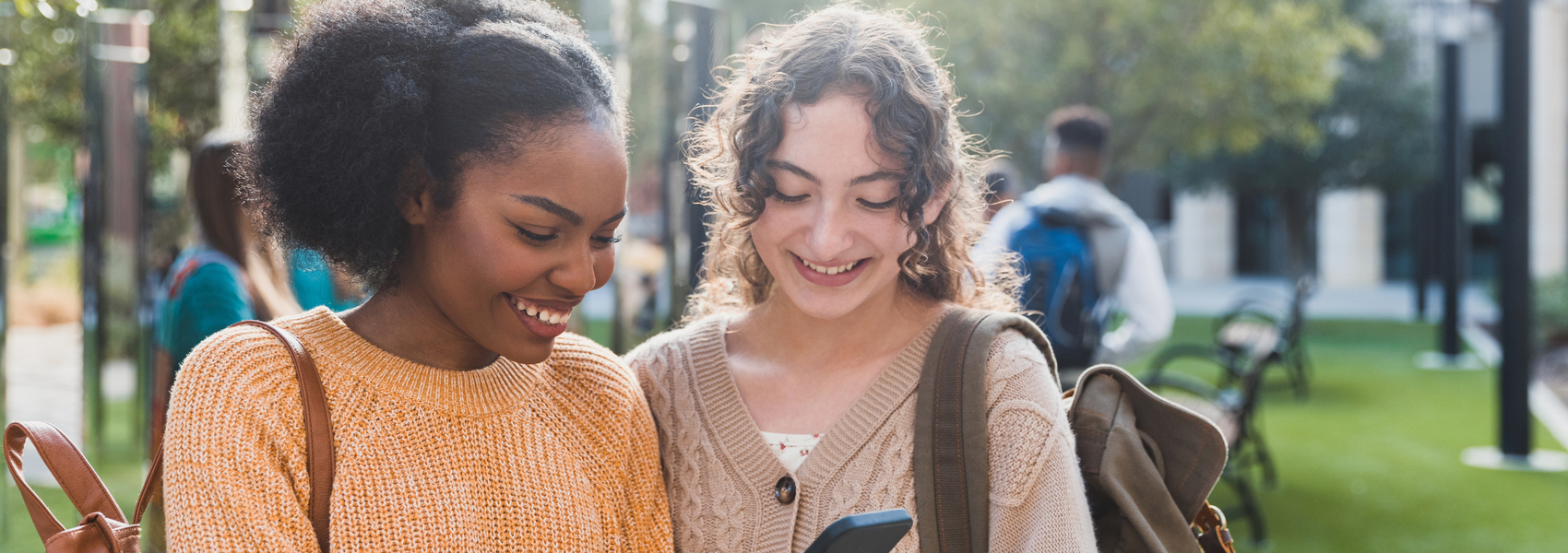 Two teen girls look at their phone